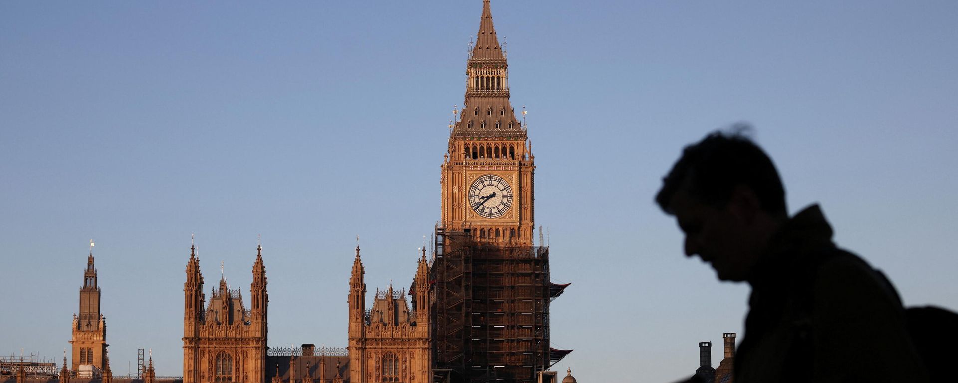 The Houses of Parliament can be seen as a person walks along the South Bank of the River Thames during sunrise, in London - Sputnik International, 1920, 18.05.2022