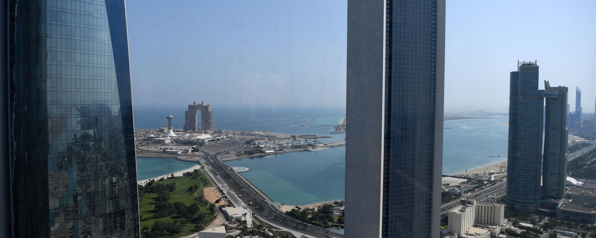 A general view shows the sea front promenade in the Emirati capital Abu Dhabi with the ADNOC headquarters (Abu Dhabi National Oil Company) office complex (C) in the foreground on May 29, 2019. - Sputnik International, 1920, 04.02.2026