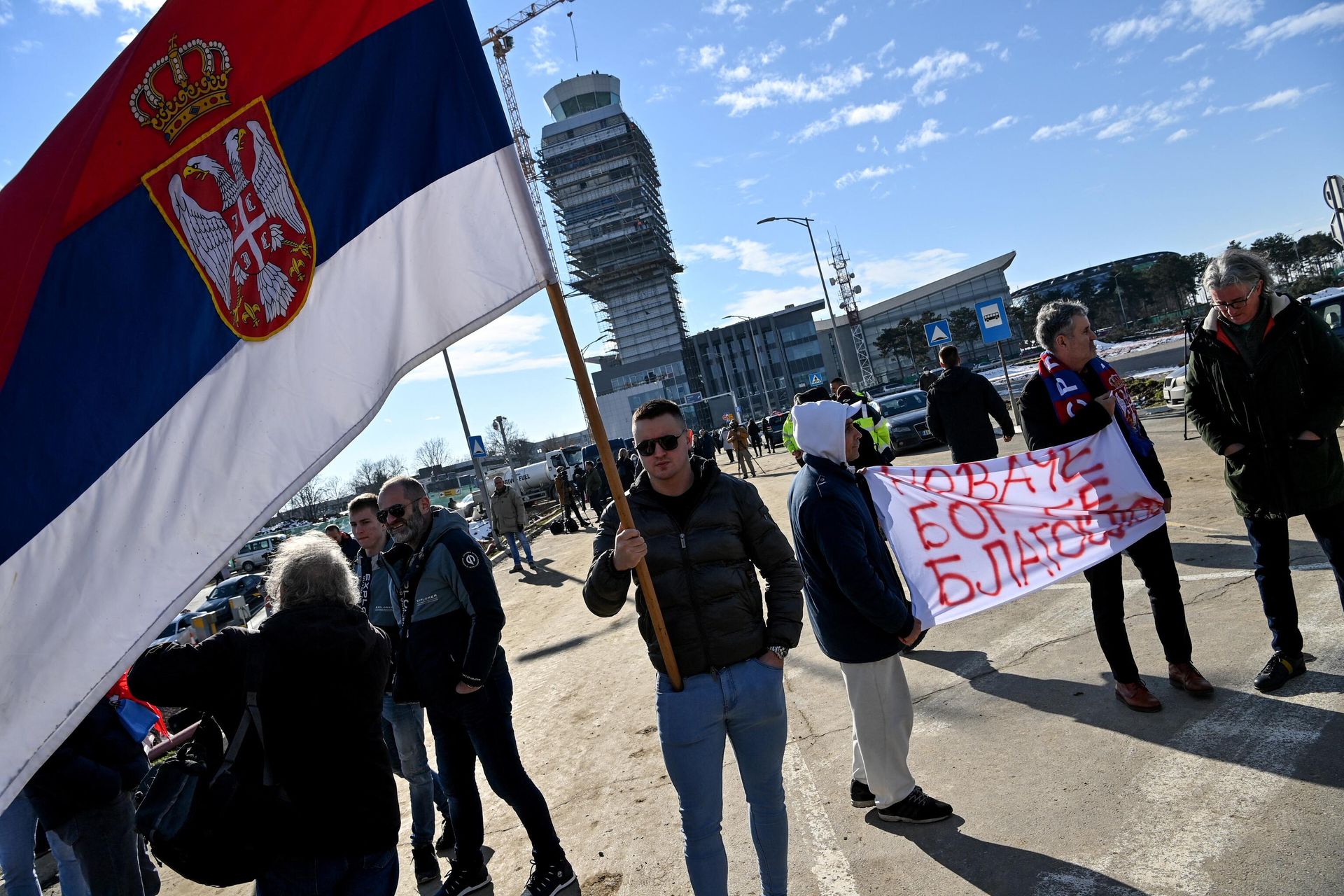 People hold a banner reading Novak, God bless you and another holds a Serbian national flag as they wait outside the VIP exit of Belgrade's international airport on 17 January 2022, for Tennis world number one Novak Djokovic's arrival after his deportation from Australia over his coronavirus vaccination status. - Sputnik International, 1920, 20.01.2022