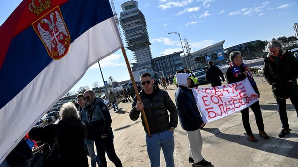 People hold a banner reading Novak, God bless you and another holds a Serbian national flag as they wait outside the VIP exit of Belgrade's international airport on 17 January 2022, for Tennis world number one Novak Djokovic's arrival after his deportation from Australia over his coronavirus vaccination status. - Sputnik International