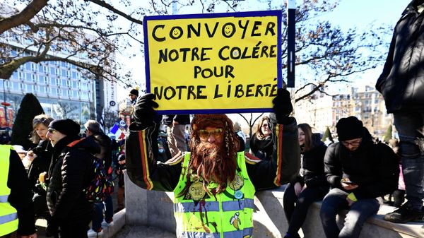 A demonstrator wearing a yellow vest holds a sign reading Let's convoy our anger for our liberty as he gathers with other protestors at the Place d'Italie in Paris on February 12, 2022 as convoys of protesters from the Convoi de la Liberte arrive in the French capital. - Sputnik International