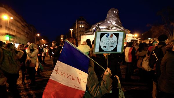 Protesters hold a French flag and a sign reading 'I support the freedom convoy' at Place Denfert-Rochereau in southern Paris on February 11, 2022. - Sputnik International
