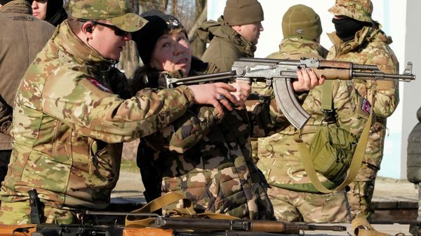 An instructor shows a woman how to use a Kalashnikov assault rifle, as members of a Ukrainian far-right group train, in Kyiv, Ukraine, Sunday, Feb. 13, 2022. Russia denies it intends to invade but has massed well over 100,000 troops near the Ukrainian border and has sent troops to exercises in neighboring Belarus, encircling Ukraine on three sides. U.S. officials say Russia's buildup of firepower has reached the point where it could invade on short notice. - Sputnik International