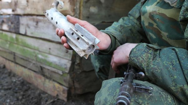 Donbass militiaman holds up piece of shell fired on his comrades' position by Kiev forces in Western Donetsk. 15 February 2022. - Sputnik International