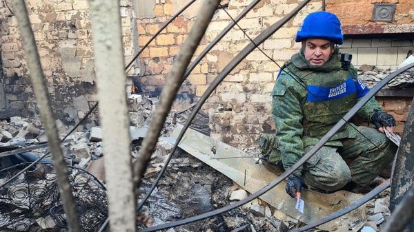 A representative of the Joint Centre for Control and Coordination of the Ceasefire Regime (JCCC) of the LPR near the house that was hit by an artillery strike by the Ukrainian Armed Forces on the village of Pionerskoye in the LPR. - Sputnik International