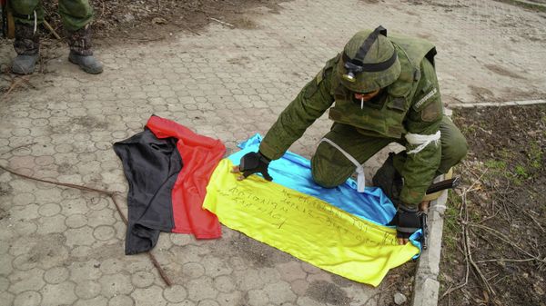 A serviceman of militia of Donetsk People's Republic (DPR) demonstrates flags of Ukraine and of Right Sector right-wing   radical group (banned in Russia) found in a camp of Ukrainian forces outside Mariupol, Ukraine - Sputnik International