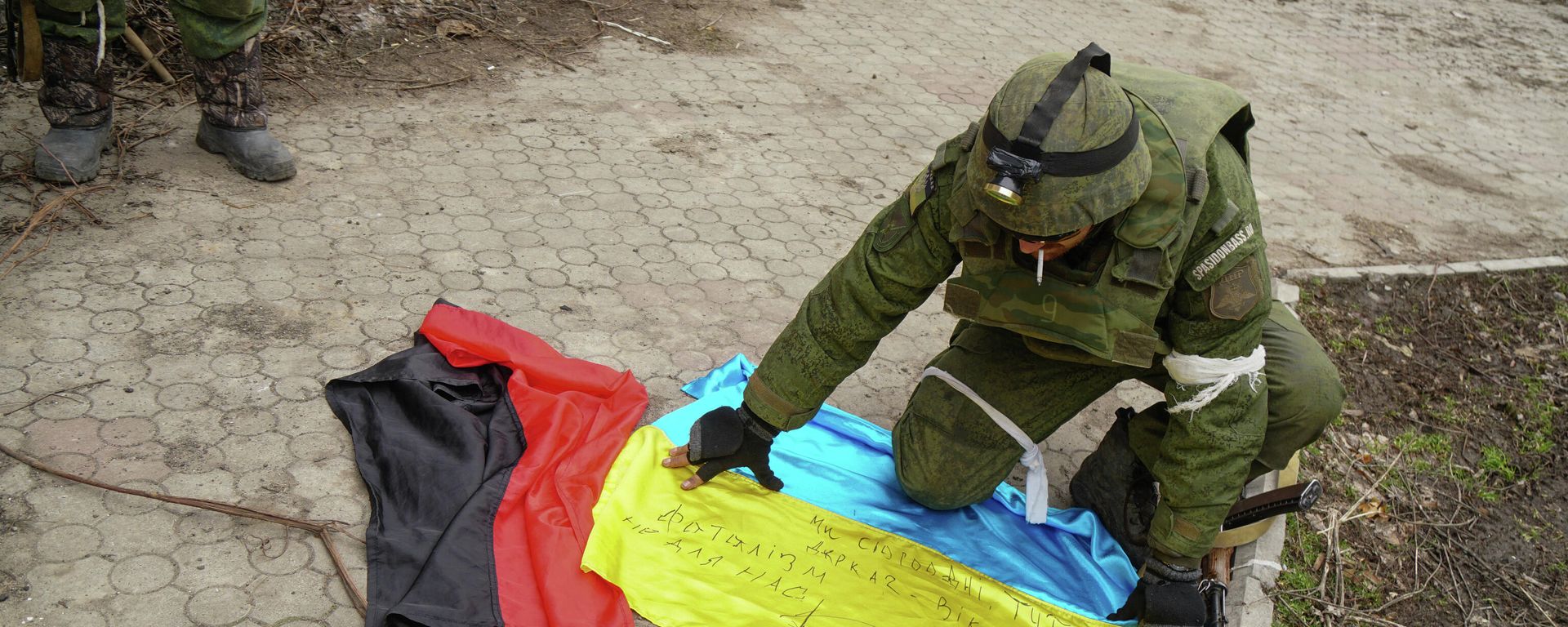 A serviceman of militia of Donetsk People's Republic (DPR) demonstrates flags of Ukraine and of Right Sector right-wing   radical group (banned in Russia) found in a camp of Ukrainian forces outside Mariupol, Ukraine - Sputnik International, 1920, 06.03.2022