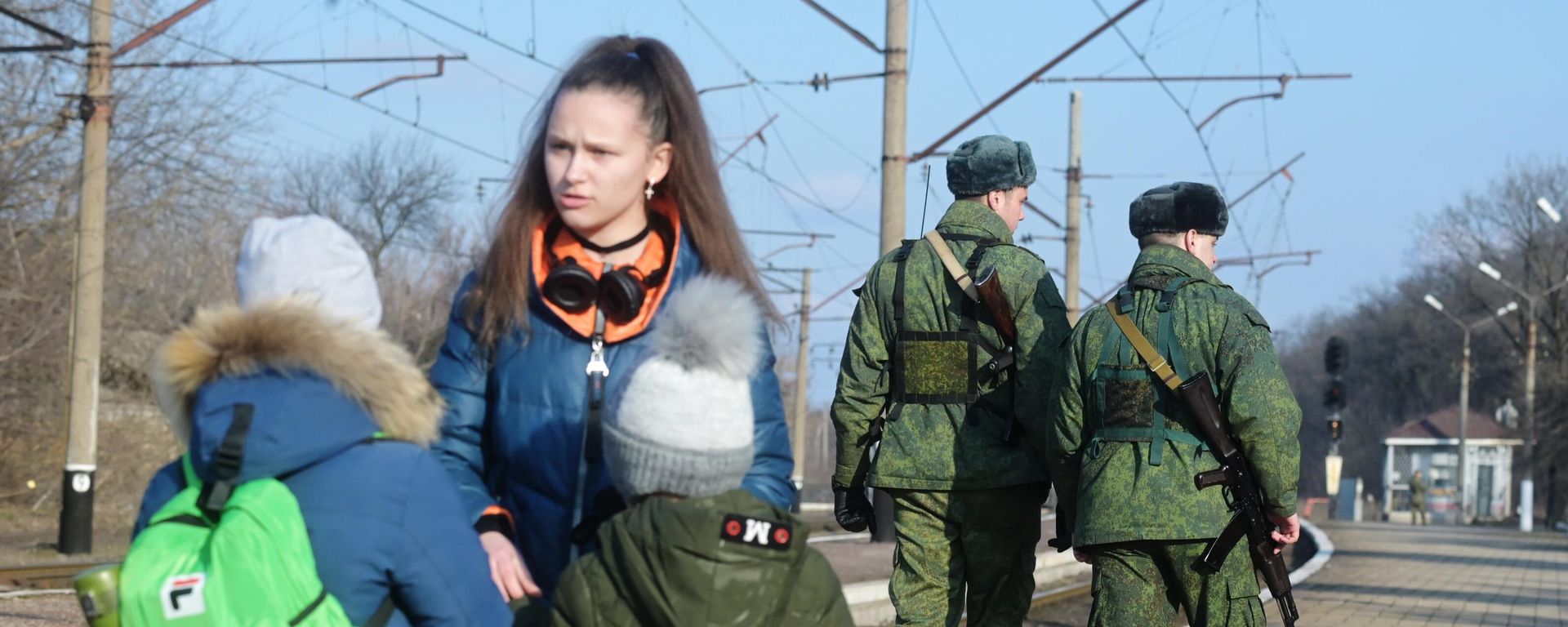 Armed people patrol the railway platform while residents wait for a train at the station in Makeevka to evacuate to Russia Armed people patrol the railway platform while residents wait for a train at the station in Makeevka to evacuate to Russia - Sputnik International, 1920, 04.03.2022