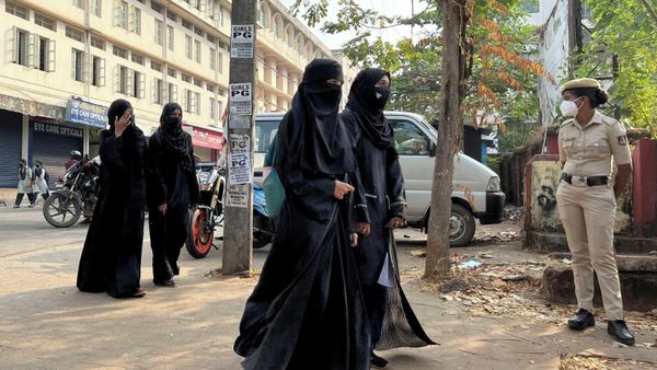 Hijab-wearing students arrive to attend classes as a policewoman stands guard outside a government girls school after the recent hijab ban, in Udupi town in the southern state of Karnataka, India, February 16, 2022 - Sputnik International