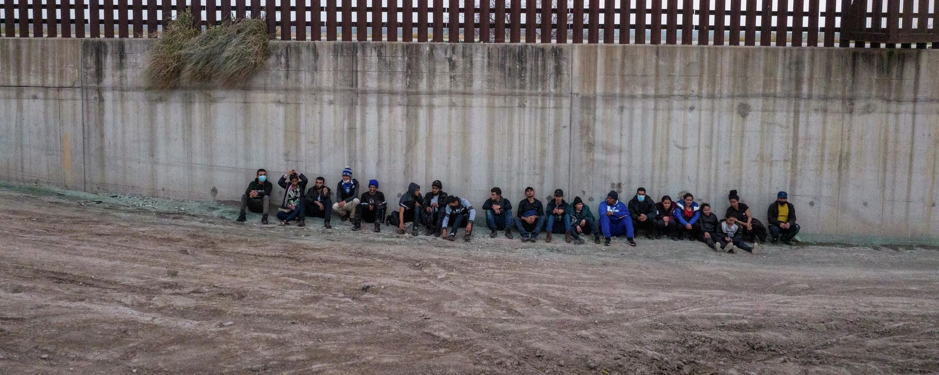 Asylum seeking migrants from Central America line up near the border wall as they await to be processed by agents after crossing the Rio Grande river into the United States from Mexico in Penitas, Texas, U.S., February 23, 2022. Picture taken with a drone. - Sputnik International, 1920, 02.04.2022