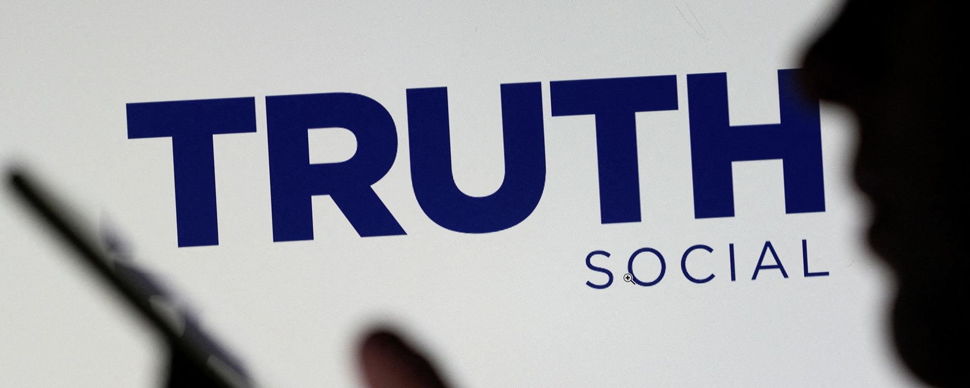 The Truth social network logo is seen displayed behind a woman holding a smartphone in this picture illustration taken February 21, 2022. - Sputnik International, 1920, 23.03.2022