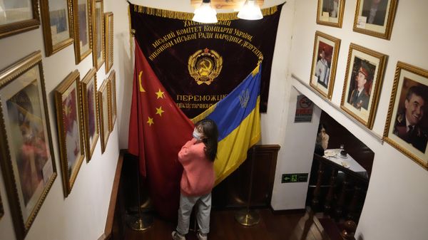 A visitor to a Ukraine restaurant holds together the Chinese and Ukraine national flags as she poses for a photo on Thursday, Feb. 24, 2022, in Beijing. - Sputnik International