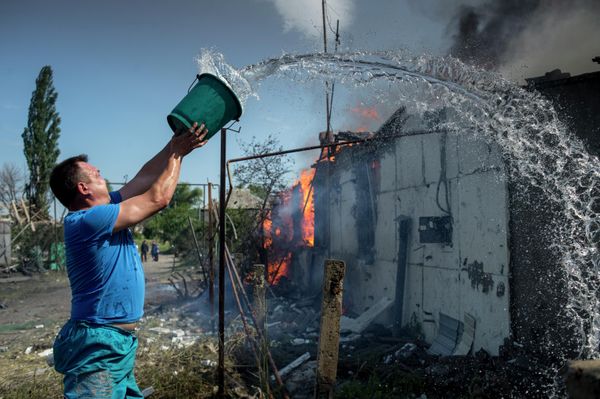 July 2014: Stanitsa Luganskaya: Local resident attempts to put out fire following a Ukrainian air raid. - Sputnik International