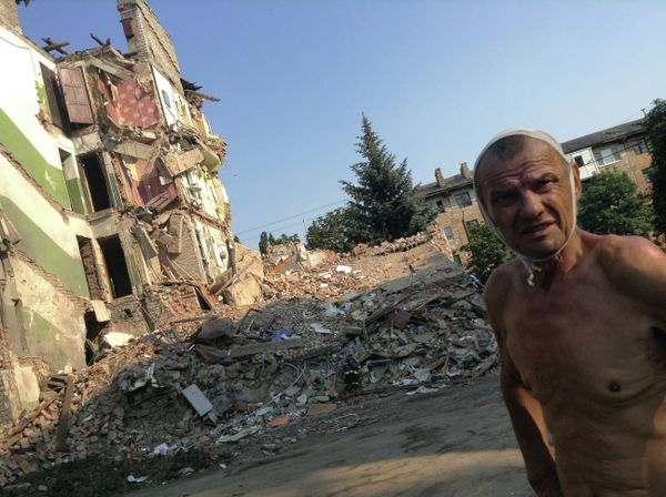 July 2014: 70-year-old Snezhnoe resident Viktor Stepanenko outside his apartment building, leveled by a Ukrainian missile. His wife and 11 others were killed in the attack. Stepanenko miraculously managed to survive after falling out of the fourth floor of the apartment bloc onto a spruce tree growing nearby. - Sputnik International