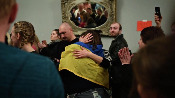A woman wearing a Ukrainian National Flag is huged as volunteers collect and pack primary goods to be sent to Poland for Ukrainian refugees, at the White Eagle Club, a Polish social centre, in Balham, in south London, on March 2, 2022 - Sputnik International