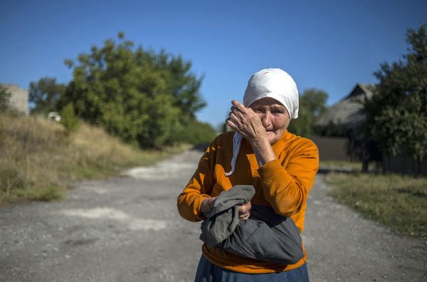 A woman wipes away tears near a convoy of vehicles from the 38th Russian humanitarian convoy to Donetsk in September 2015. For many residents of Donbass, humanitarian aid convoys consisting of food, medicines, and basic hygiene products became critical to survival.  - Sputnik International