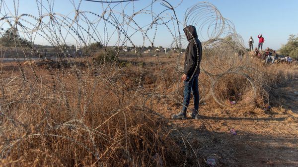 Palestinians gather by a section of Israel's separation barrier, while they wait for the Israeli army to allow them to cross the fence, in the West Bank village of Nilin, west of Ramallah, Sunday, Nov. 7, 2021. - Sputnik International