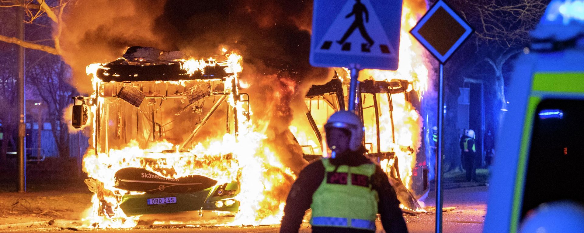 An anti-riot police officer stands next to a city bus burning in Malmo late April 16, 2022. - The unrest in Malmo has continued after Rasmus Paludan, party leader of the Danish right-wing extremist party Tight Course, held a demonstration on April 16, 2022 at Skanegarden near the Oresund Bridge. (Photo by Johan NILSSON / TT NEWS AGENCY / AFP)  - Sputnik International, 1920, 20.04.2022