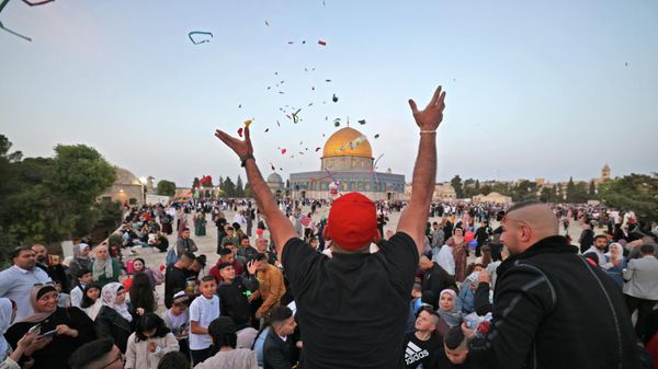 A Muslim man hands out sweets in front of the Dome of the Rock mosque after the morning Eid al-Fitr prayer, which marks the end of the holy fasting month of Ramadan, at the Al-Aqsa mosques compound in Old Jerusalem early on May 2, 2022. - Sputnik International