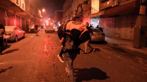 A man carries an injured rescue personnel during clashes between Israeli police and Palestinians, folowing the funeral of Palestinian Waleed Shareef, in east Jerusalem, Monday, May 16, 2022. - Sputnik International