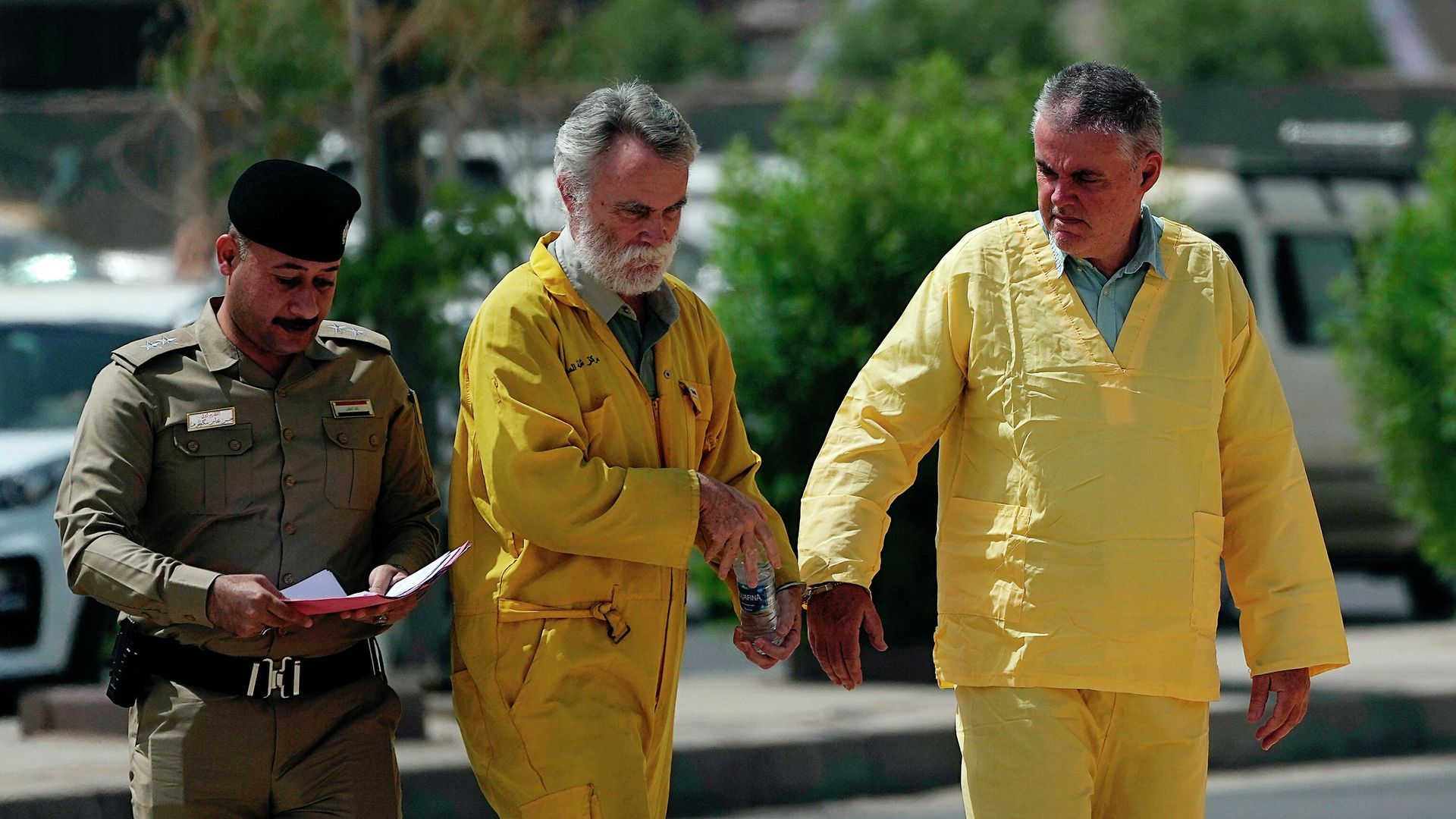 Volker Waldmann, right, and Jim Fitton, center, are handcuffed as they walk to a courtroom in Baghdad, Iraq, Sunday, May 22, 2022 - Sputnik International, 1920, 06.06.2022