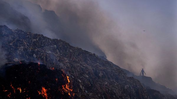 A ragpicker looks for reusable items while a fire rages at the Bhalswa landfill in New Delhi, Wednesday, April 27, 2022 - Sputnik International