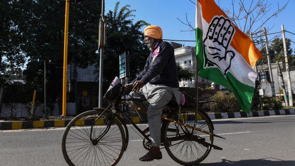 A Congress party supporter rides a bicycle with a party flag  (File) - Sputnik International