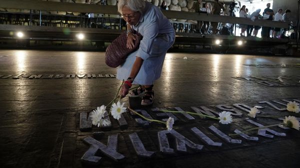 A woman places a flower on a marker for the Auschwitz concentration camp in the Hall of Remembrance during the Holocaust Martyrs and Heroes Remembrance Day at the Yad Vashem Holocaust Museum in Jerusalem, Thursday, April 28, 2022. (AP Photo/Maya Alleruzzo) - Sputnik International