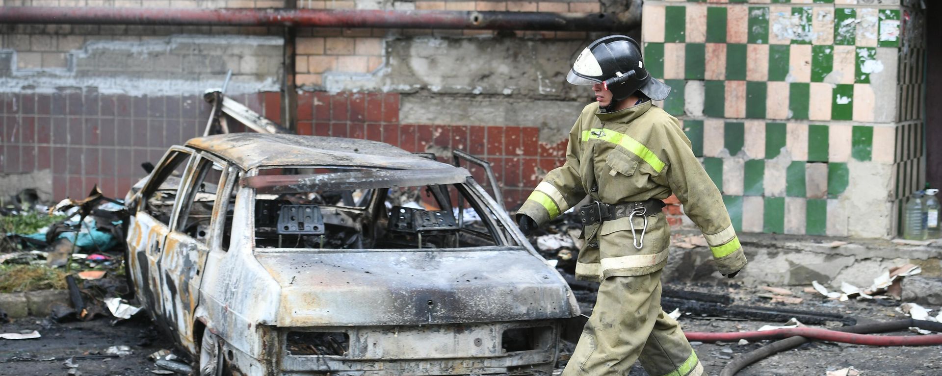 An employee of the Ministry of Emergency Situations of the DPR near a residential building that burned down as a result of shelling of Donetsk by the Armed Forces of Ukraine. - Sputnik International, 1920, 12.12.2022
