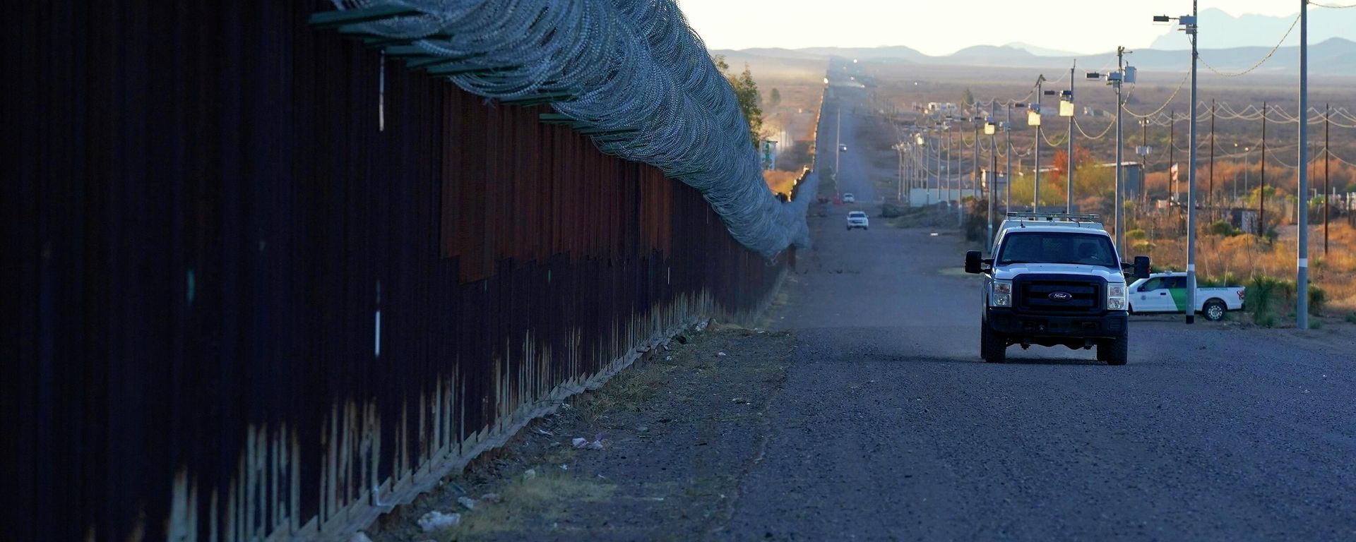 A U.S. Border Patrol vehicle drives along the border fence at the U.S.-Mexico border wall, on Dec. 15, 2020, in Douglas, Ariz. Authorities are investigating the cause of death of a female migrant whose leg was entrapped while using a climbing harness and ended up hanging upside down off the border wall in eastern Arizona. U.S. Customs and Border Protection officials offered few details, but the local sheriff's office said the woman was a 32-year-old Mexican who was attempting to cross the wall Monday, April 11, 2022 near Douglas, Arizona. Her name was not released. A U.S. Border Patrol vehicle drives along the border fence at the U.S.-Mexico border wall, on Dec. 15, 2020, in Douglas, Ariz. Authorities are investigating the cause of death of a female migrant whose leg was entrapped while using a climbing harness and ended up hanging upside down off the border wall in eastern Arizona. U.S. Customs and Border Protection officials offered few details, but the local sheriff's office said the woman was a 32-year-old Mexican who was attempting to cross the wall Monday, April 11, 2022 near Douglas, Arizona. Her name was not released. - Sputnik International, 1920, 27.09.2023
