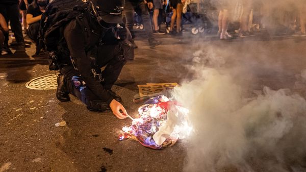 A protester lights a cigarette on a burning American Flag while marching with abortion-rights activists following the announcement to the Dobbs v Jackson Women's Health Organization ruling on June 24, 2022 in Washington, DC - Sputnik International