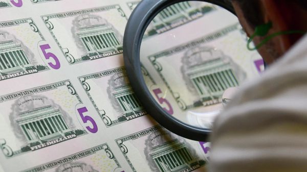 An employee examines a sheet of 5 USD notes as it comes off the printing machine  at the US Treasury's Bureau of Engraving and Printing in Washington, DC July 20, 2018. - Sputnik International