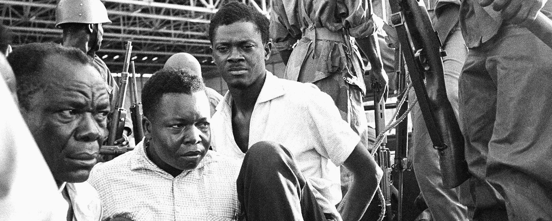 Congo's former prime minister Patrice Lumumba, center right, with hands tied behind his back, sits in a truck upon arrival at Leopoldville (now Kinshasa) Airport in Congo, Dec. 2, 1960, following his arrest the previous day. On Monday, more than sixty one years after his death, the mortal remains of Congo's first democratically elected prime minister Patrice Lumumba will be handed over to his children during an official ceremony in Belgium. - Sputnik International, 1920, 30.06.2022