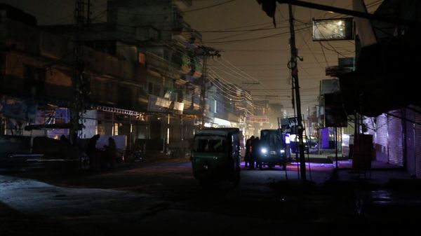 People and auto rickshaws are silhouetted on vehicles headlights on a dark street during widespread power outages in Rawalpindi, Pakistan, Sunday, Jan. 10, 2021. - Sputnik International