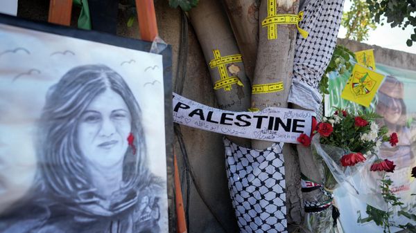 Yellow tape marks bullet holes on a tree and a portrait and flowers create a makeshift memorial on o May 19, 2022, at the site where Palestinian-American Al-Jazeera journalist Shireen Abu Akleh was shot and killed in the West Bank city of Jenin. The Palestinian Authority on Saturday, July 2, 2022, said it has given the bullet that killed Al Jazeera journalist Shireen Abu Akleh to American forensic experts, taking a step toward resolving a standoff with Israel over the investigation into her death.  - Sputnik International