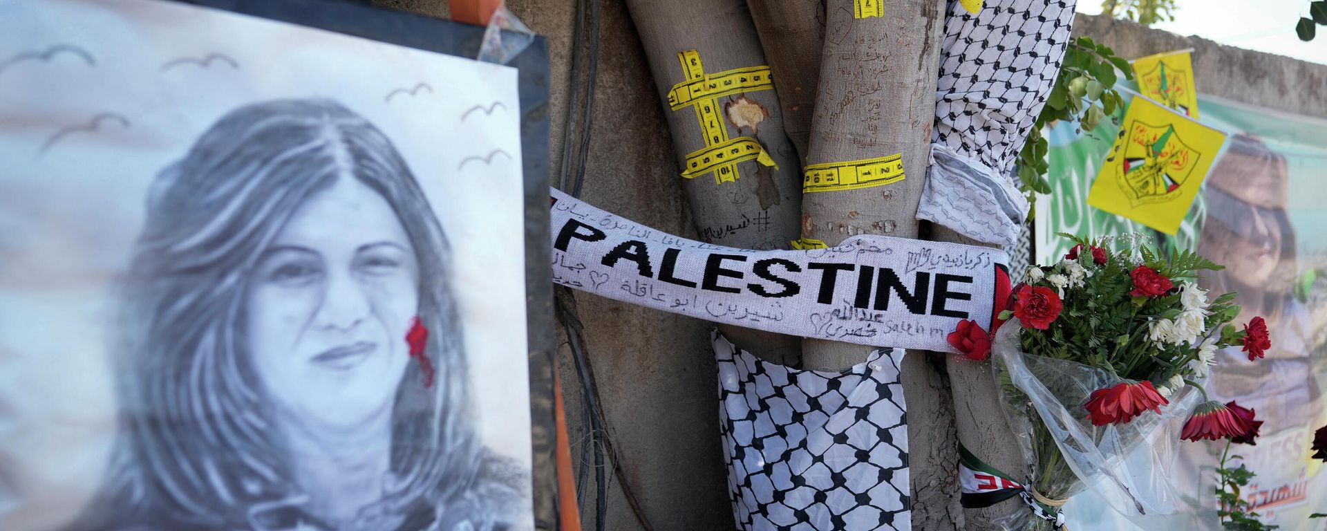 Yellow tape marks bullet holes on a tree and a portrait and flowers create a makeshift memorial on o May 19, 2022, at the site where Palestinian-American Al-Jazeera journalist Shireen Abu Akleh was shot and killed in the West Bank city of Jenin. The Palestinian Authority on Saturday, July 2, 2022, said it has given the bullet that killed Al Jazeera journalist Shireen Abu Akleh to American forensic experts, taking a step toward resolving a standoff with Israel over the investigation into her death.  - Sputnik International, 1920, 04.07.2022