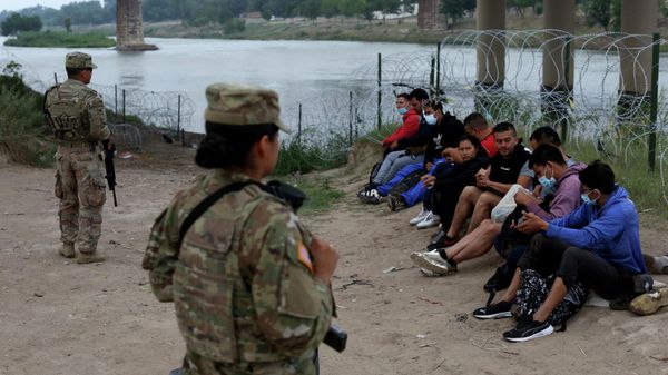 Migrants who had crossed the Rio Grande river into the U.S. are under custody of National Guard members as they await the arrival of U.S. Border Patrol agents in Eagle Pass, Texas, Friday, May 20, 2022 - Sputnik International