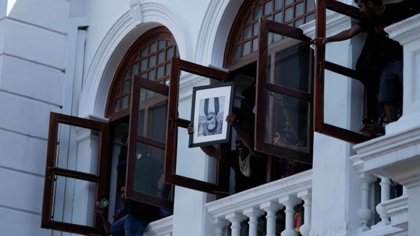 A protester holds a portrait of former Sri Lankan prime minister Mahinda Rajapaksa upside down after storming the Prime Minister Ranil Wickremesinghe's office, demanding he resign after president Gotabaya Rajapaksa fled the country amid economic crisis in Colombo, Sri Lanka, Wednesday, July 13, 2022 - Sputnik International