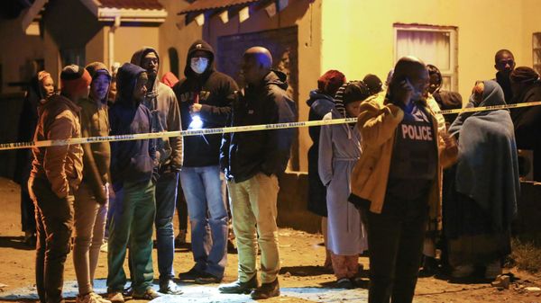 Members of the community and family wait for news outside a township pub as a police officer talks on a phone in South Africa's southern city of East London on June 26, 2022, after 20 teenagers died. - Sputnik International