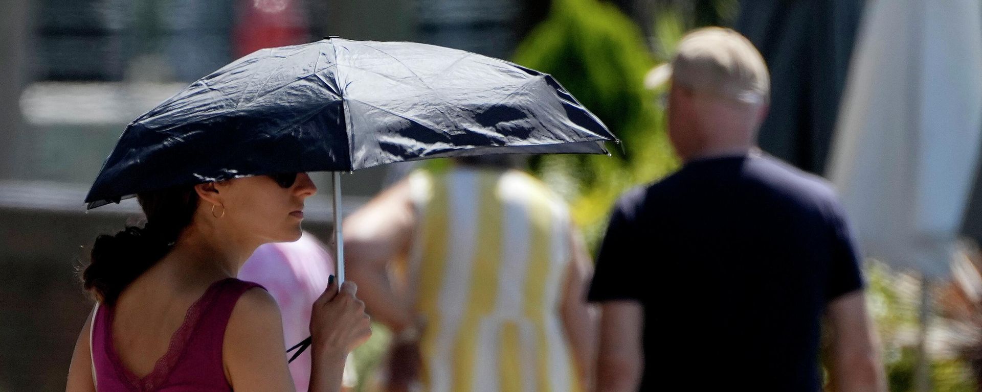 A woman uses an umbrella to shelter from the sun near Hammersmith in London, Friday, July 15, 2022. - Sputnik International, 1920, 19.07.2022