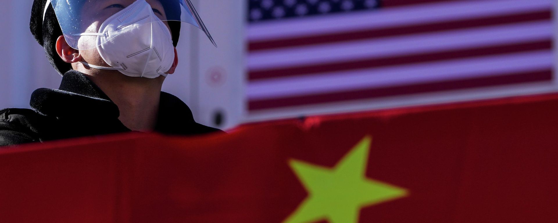 A security personnel wearing a face shield and a mask to help protect from the coronavirus stands watch at the Alpine downhill venue displaying the China and United States national flags - Sputnik International, 1920, 27.07.2022