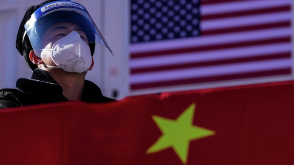A security personnel wearing a face shield and a mask to help protect from the coronavirus stands watch at the Alpine downhill venue displaying the China and United States national flags - Sputnik International