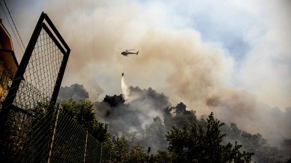 An helicopter drops water over a wildfire raging near the city of Massarosa, Tuscany region, central Italy, on July 20, 2022. (Photo by Federico SCOPPA / AFP) - Sputnik International