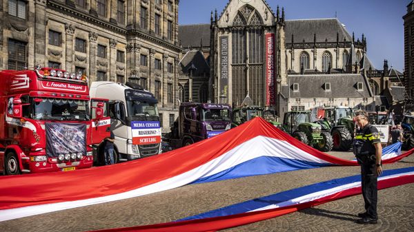 A Dutch police officer looks on at two Dutch national flags with trucks and tractors in the background during a rally of the Netherlands In Resistance group sympathizers to support farmers, fishermen and truckers, on Dam Square in Amsterdam on July 23, 2022.  - Sputnik International