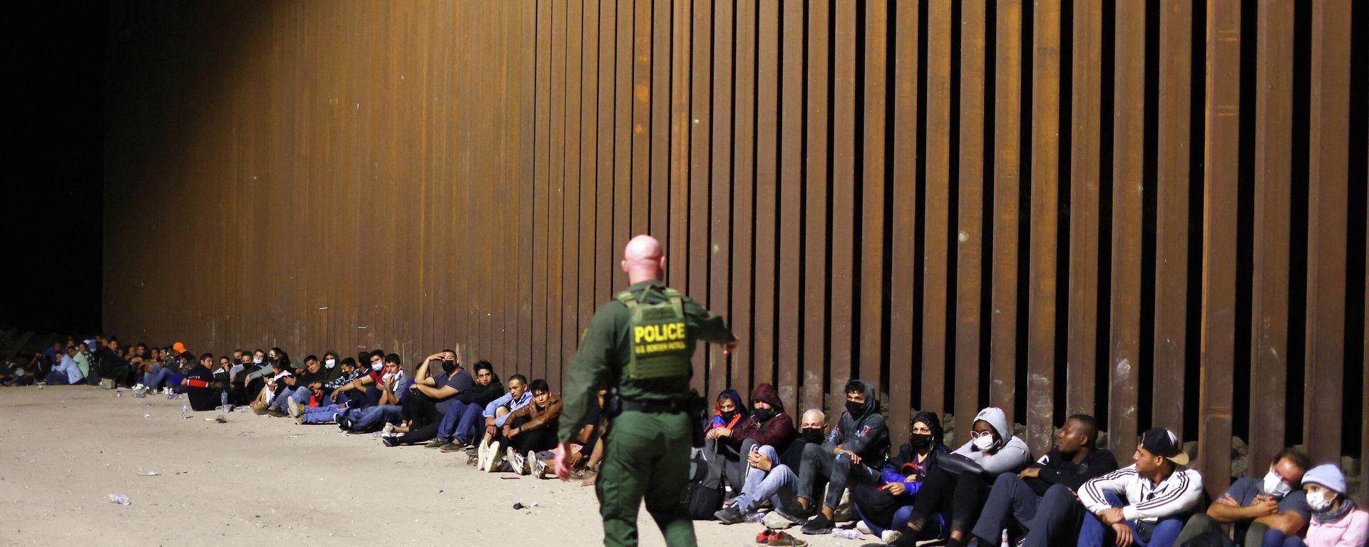 A U.S. Border Patrol agent monitors immigrants after they crossed the border with Mexico on May 18, 2022 in Yuma, Arizona - Sputnik International, 1920, 16.08.2022