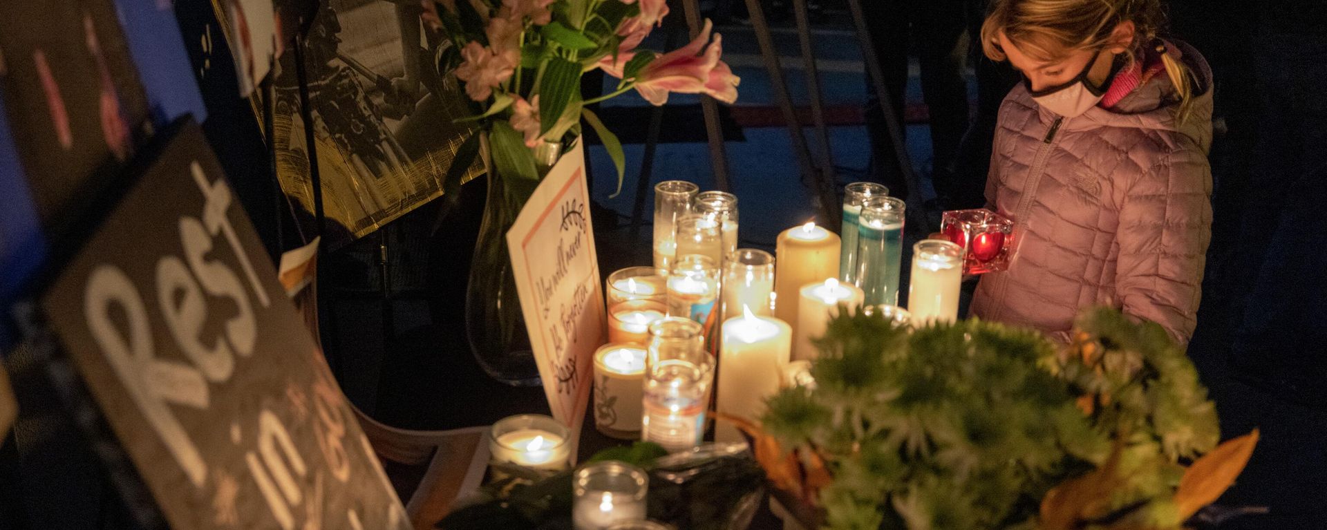 A girl pays respects near a photo of cinematographer Halyna Hutchins, who was accidentally killed by a prop gun fired by actor Alec Baldwin, at a memorial table during a candlelight vigil in her memory in Burbank, California on October 24, 2021. - Sputnik International, 1920, 14.08.2022