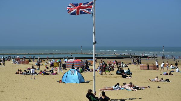 A Union flag flutters in the breeze as sunbathers take advantage of the fine weather on the beach on the coast at Margate, east of London on May 31, 2021, as fine and dry conditions continue in the UK on what could be the hottest day of the year so far - Sputnik International
