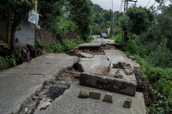 A man and woman sit next to a road, part of which has caved in because of heavy rains in Dharmshala, Himachal Pradesh state, India, Sunday, 21 August 2022. - Sputnik International