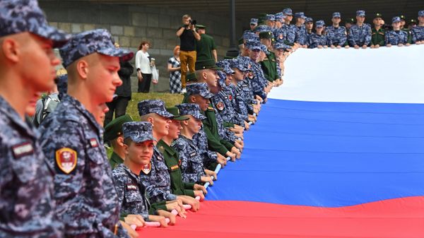 Russian military men and National Guard officers hold a huge tricolor near the Victory Museum in Moscow, August 22, 2022.  - Sputnik International