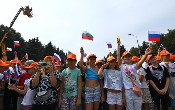 School children watch as a massive Russian tricolor flag is unfolded outside the Victory Museum in Moscow. - Sputnik International